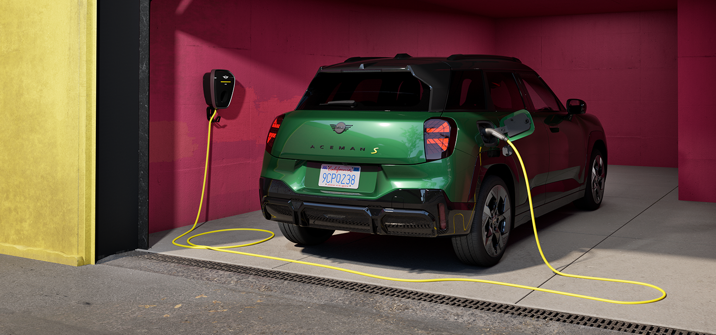 Den fuldelektriske MINI Aceman i British Racing Green set bagfra, mens den oplader i en garage. 