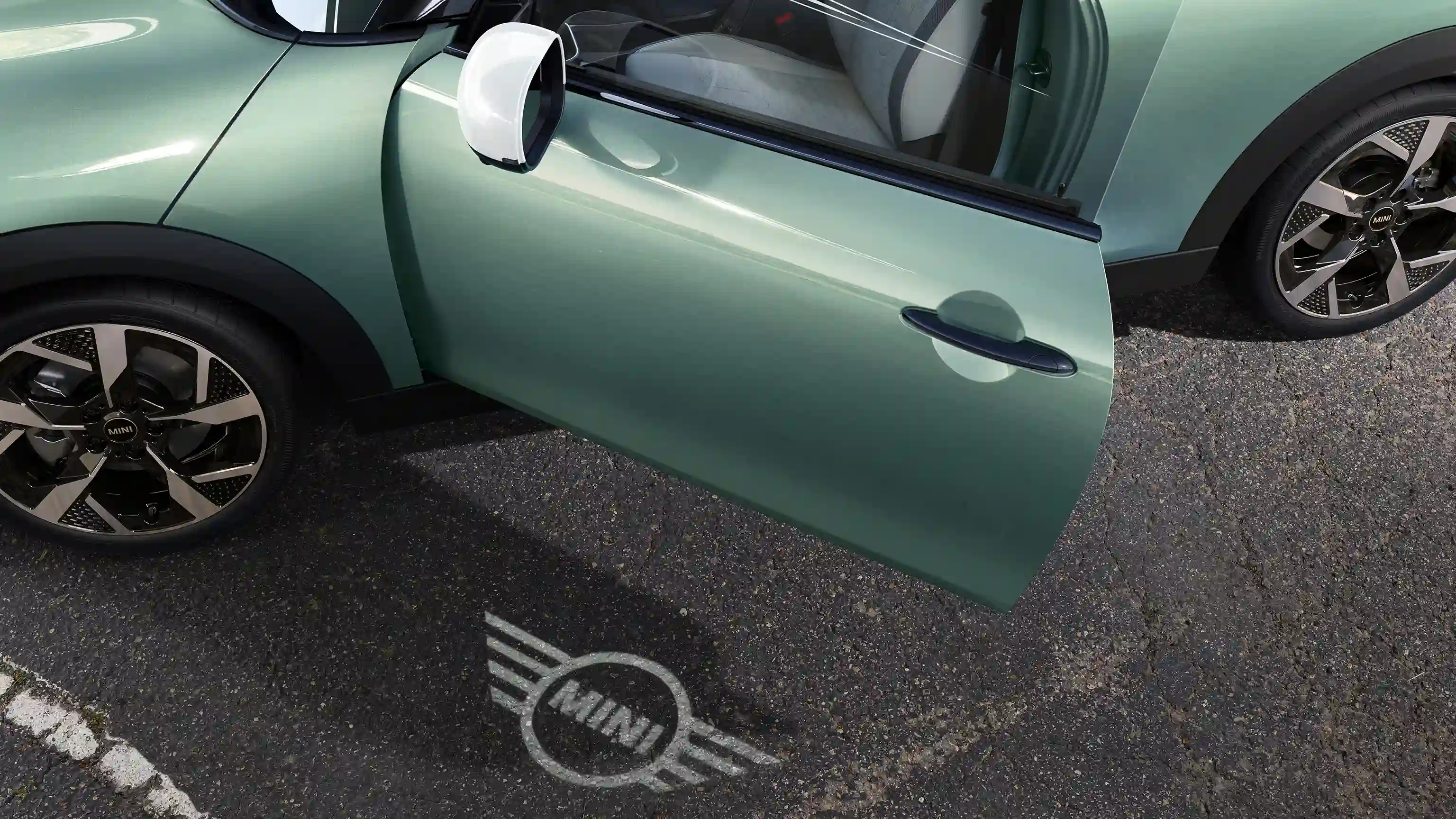 Eksteriørbillede af MINI Cooper med åben dør og MINI logoets velkomstlys på jorden 