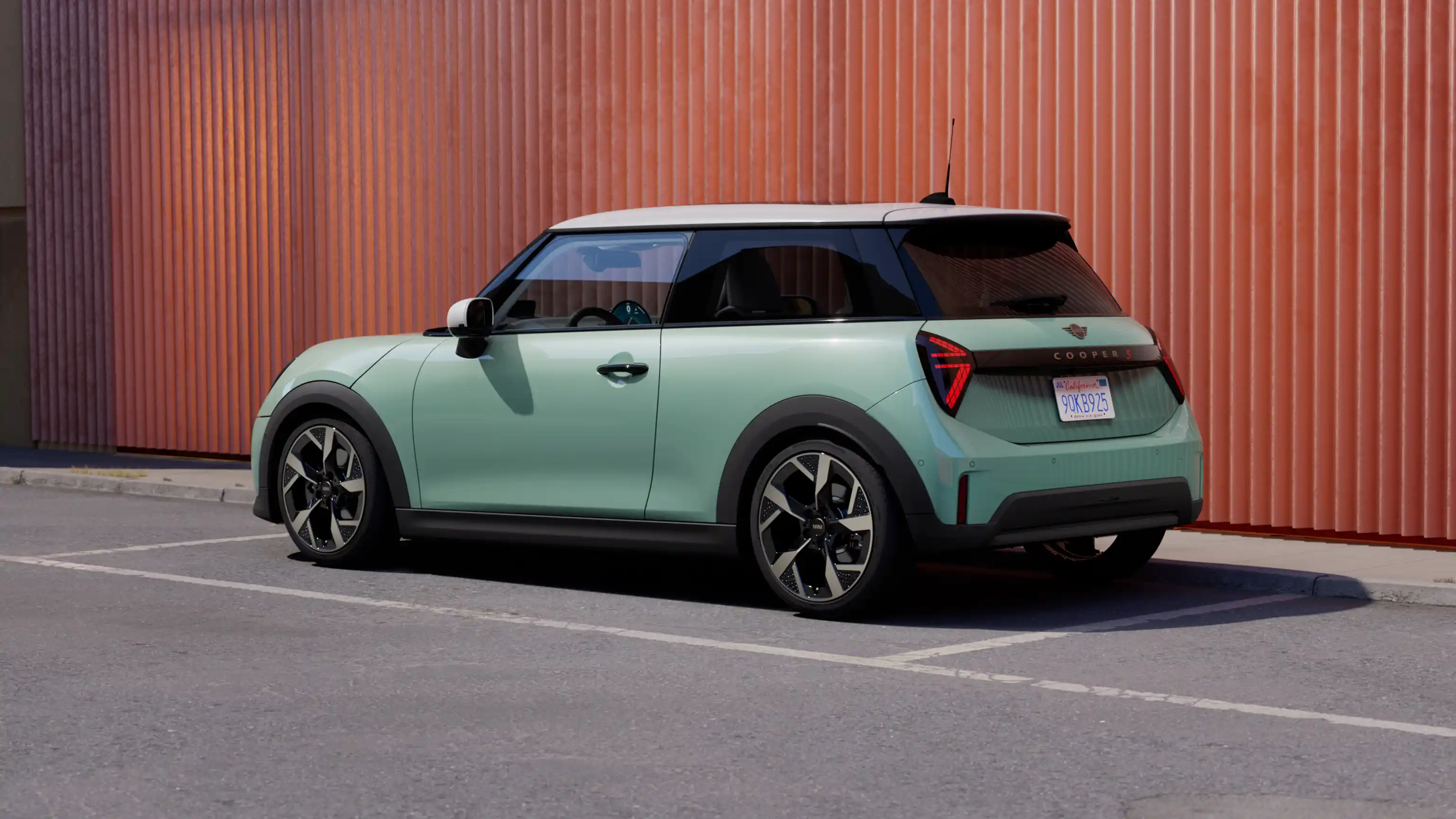 Visning af MINI Cooper i Ocean Wave Green med hvidt tag set bagfra til venstre under parkering