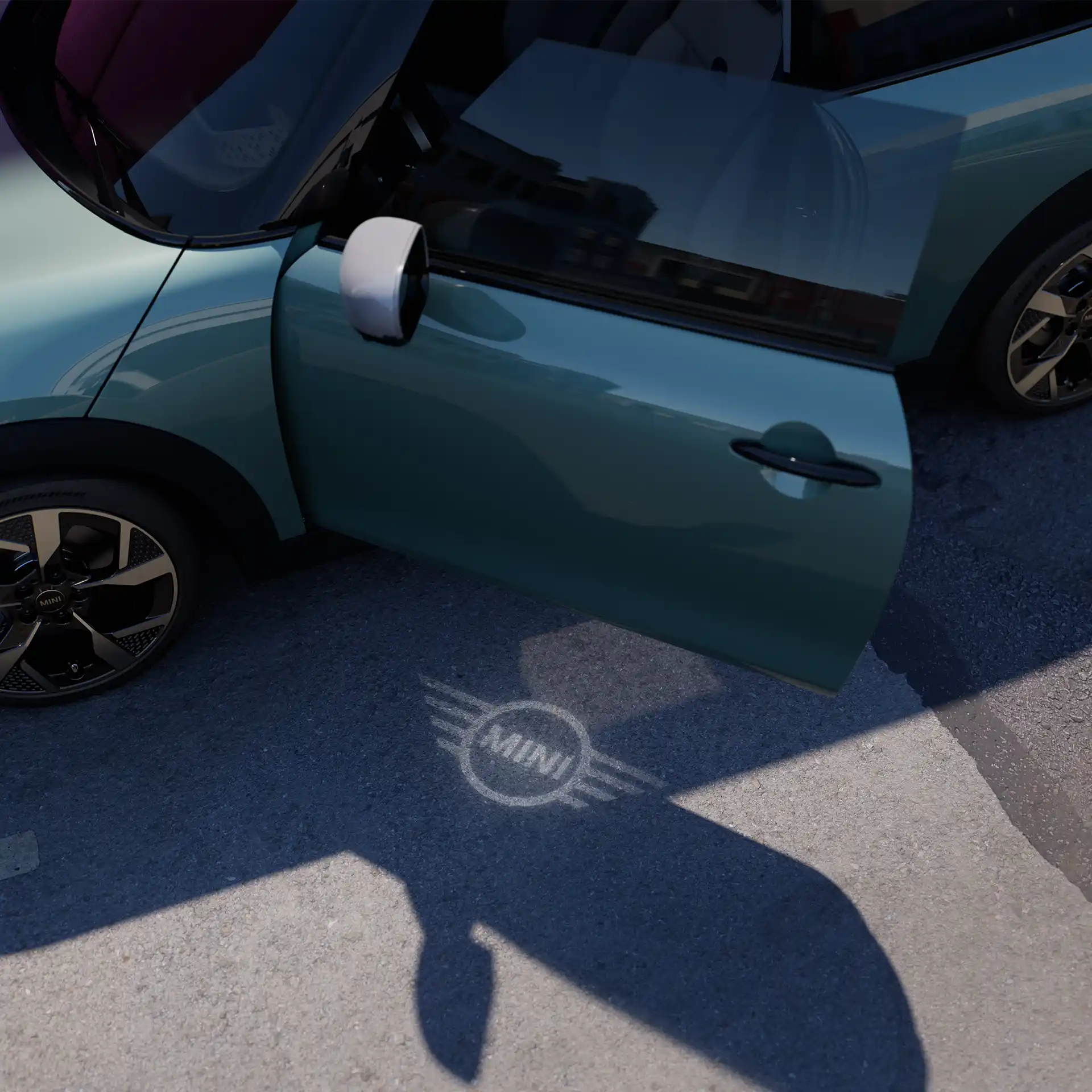 MINI Cooper set forfra med åben dør og MINI logoets velkomstlys på jorden 