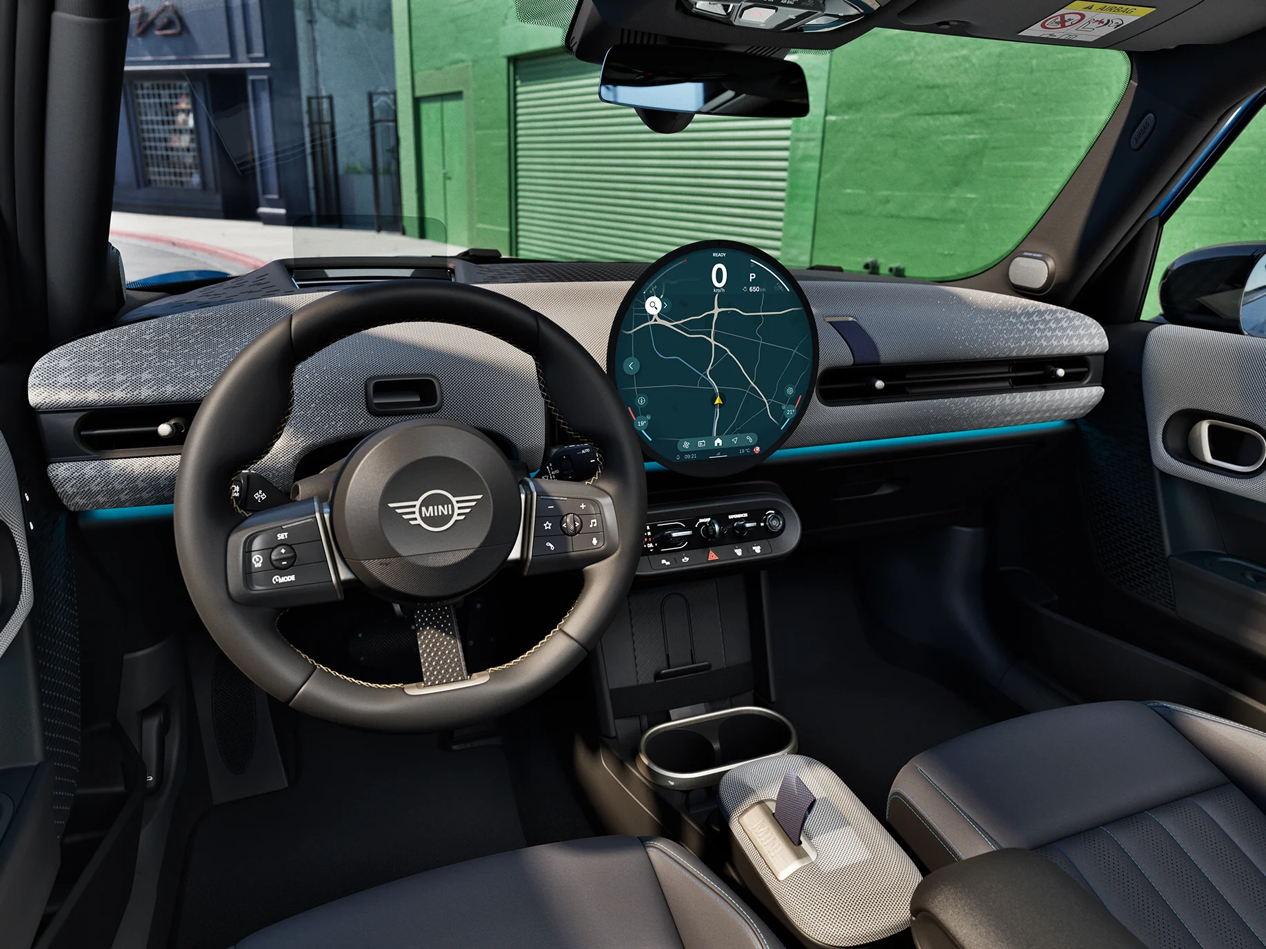 Indvendigt billede af MINI Cooper 5-dørs med fokus på rattet, instrumentbrættet og interaktionsenheden.