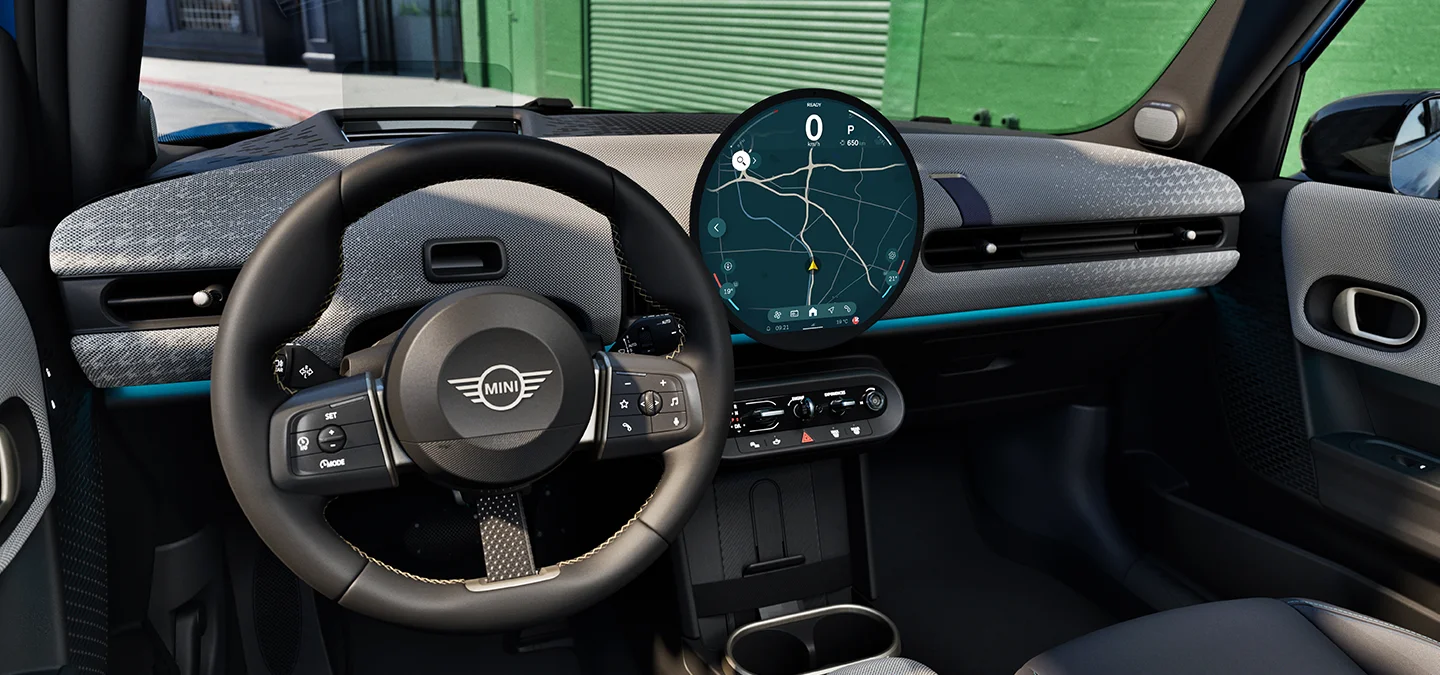 Indvendigt billede af MINI Cooper 5-dørs med fokus på rattet, instrumentbrættet og interaktionsenheden.