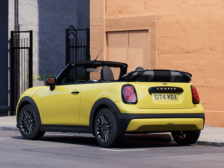 Venstre side af parkeret MINI Cooper Cabrio i Sunnyside Yellow set bagfra.