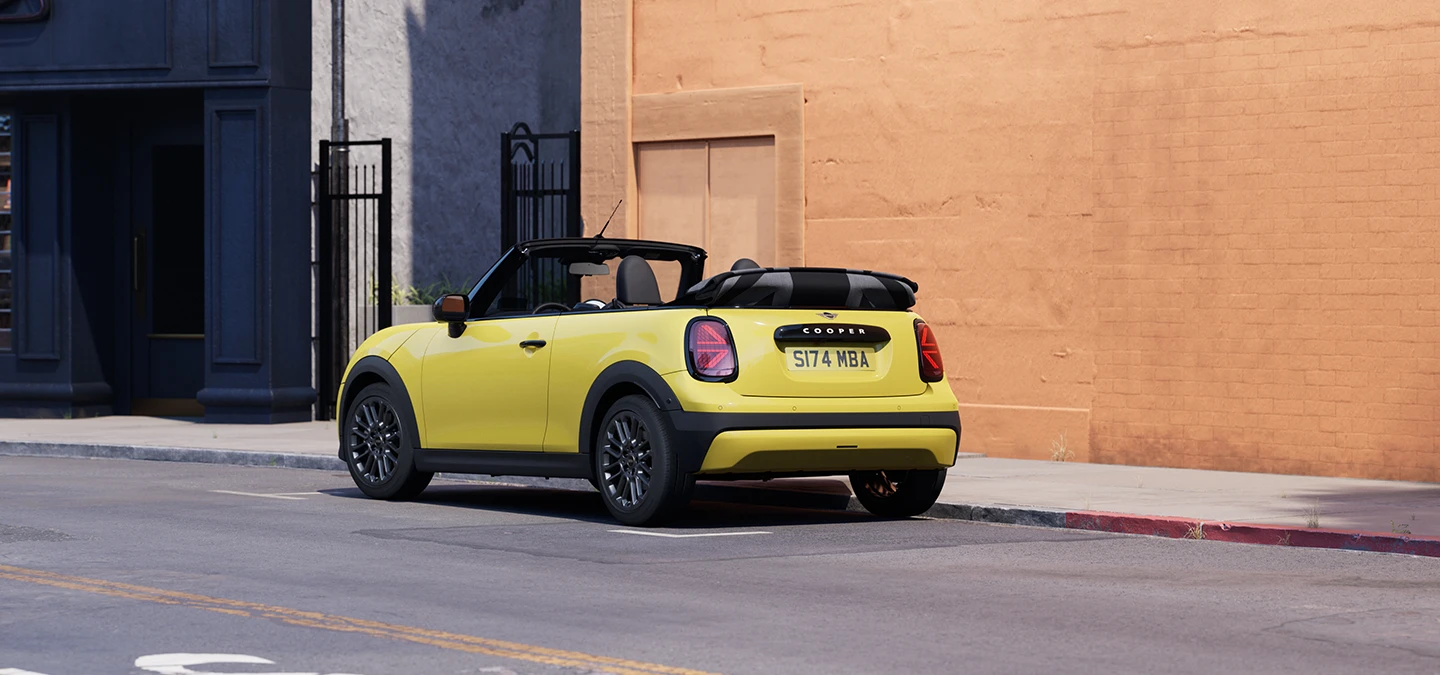 Venstre side af parkeret MINI Cooper Cabrio i Sunnyside Yellow set bagfra.