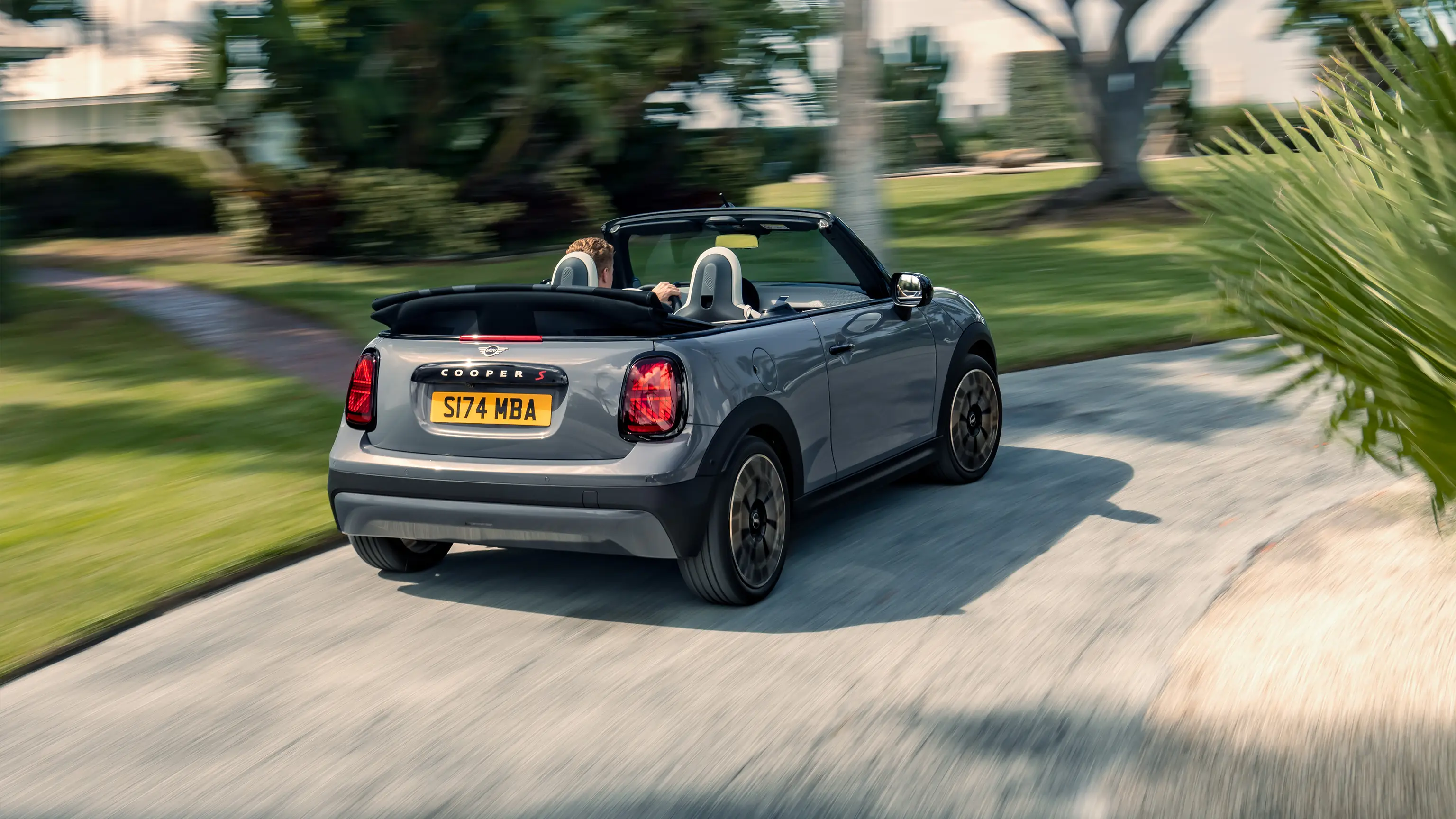 En kørende MINI Cabrio i Copper Grey set bagfra 