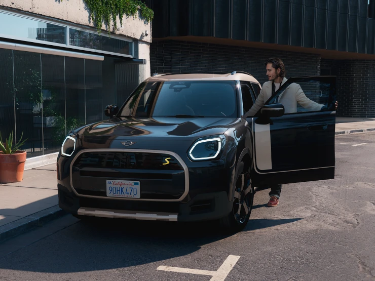 Den fuldelektriske MINI Countryman i Midnight Black set forfra med tag i Vibrant Silver på en gade.