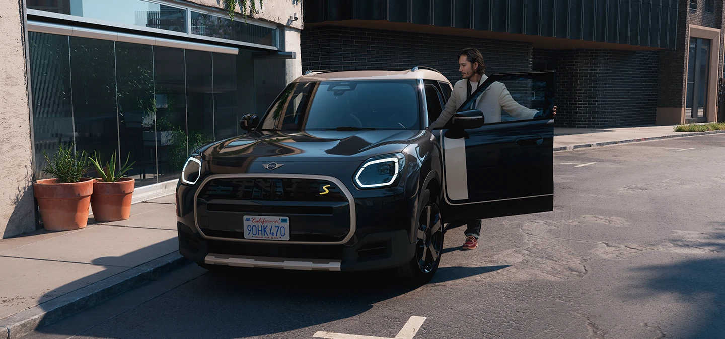 Den fuldelektriske MINI Countryman i Midnight Black set forfra med tag i Vibrant Silver på en gade.