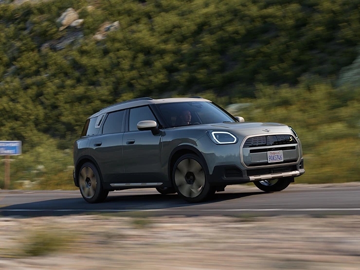 En fuldelektrisk kørende MINI Countryman i Smokey Green med tag i Vibrant Silver set fra siden.