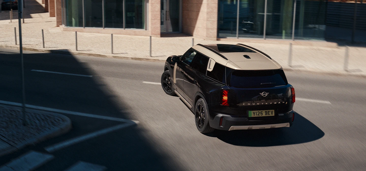 Den fuldelektriske MINI Countryman i Midnight Black med tag i Vibrant Silver set bagfra fra oven.