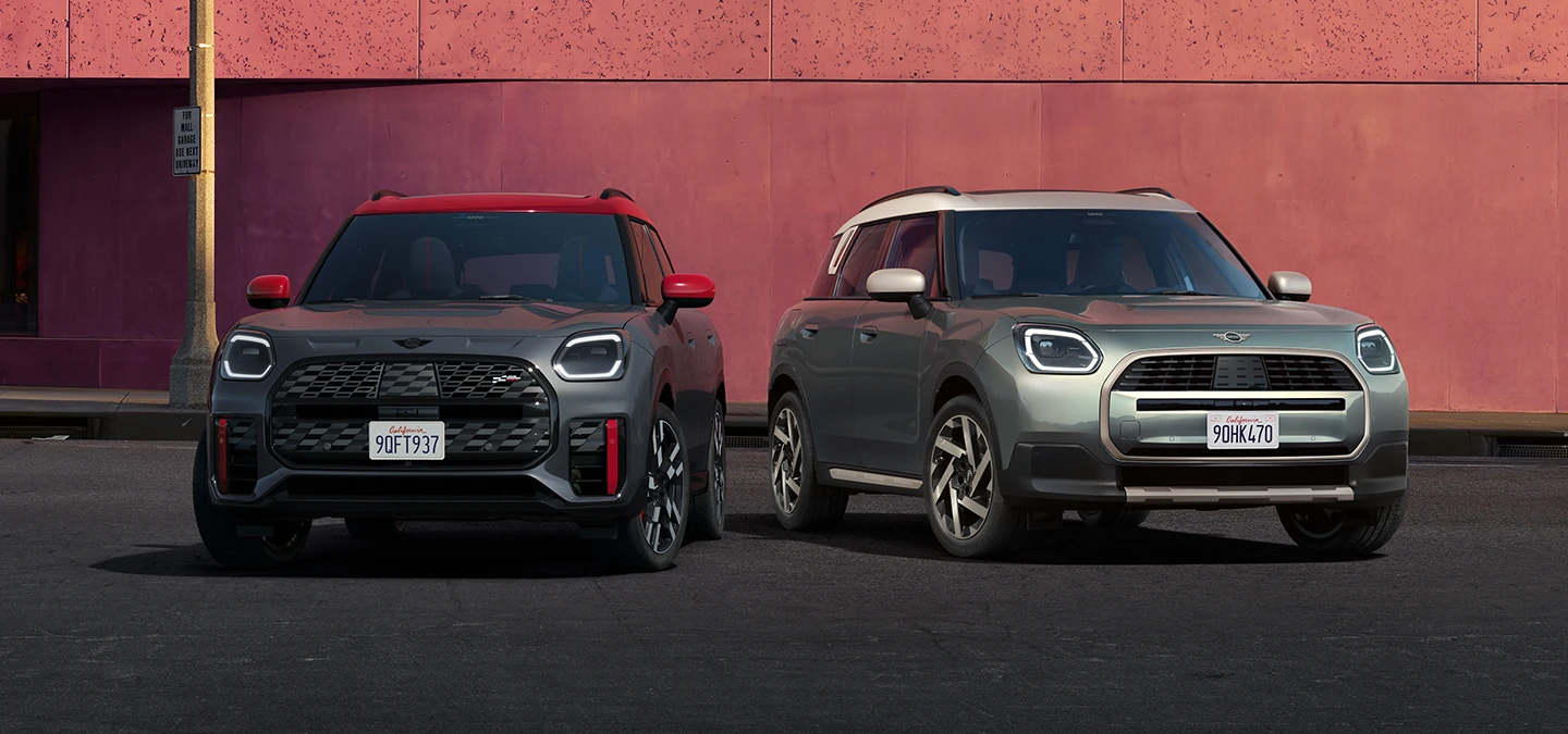 MINI Countryman JCW i Legend Grey med rødt tag set forfra og MINI Countryman i Smokey Green og tag i Vibrant Silver ved siden af hinanden.