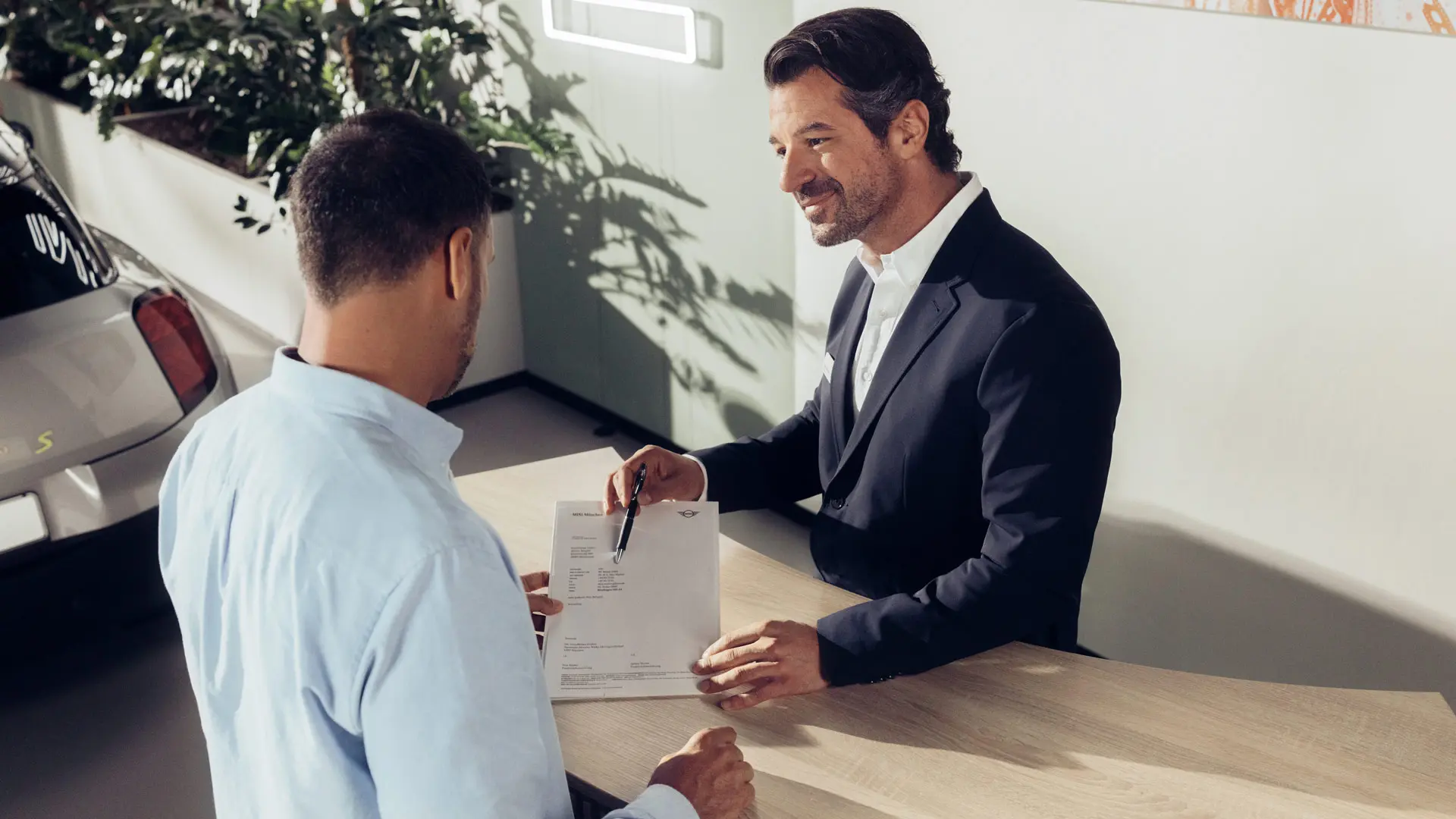 En MINI Partner specialist rådgiver en kunde om mulighederne for MINI dækforsikring.