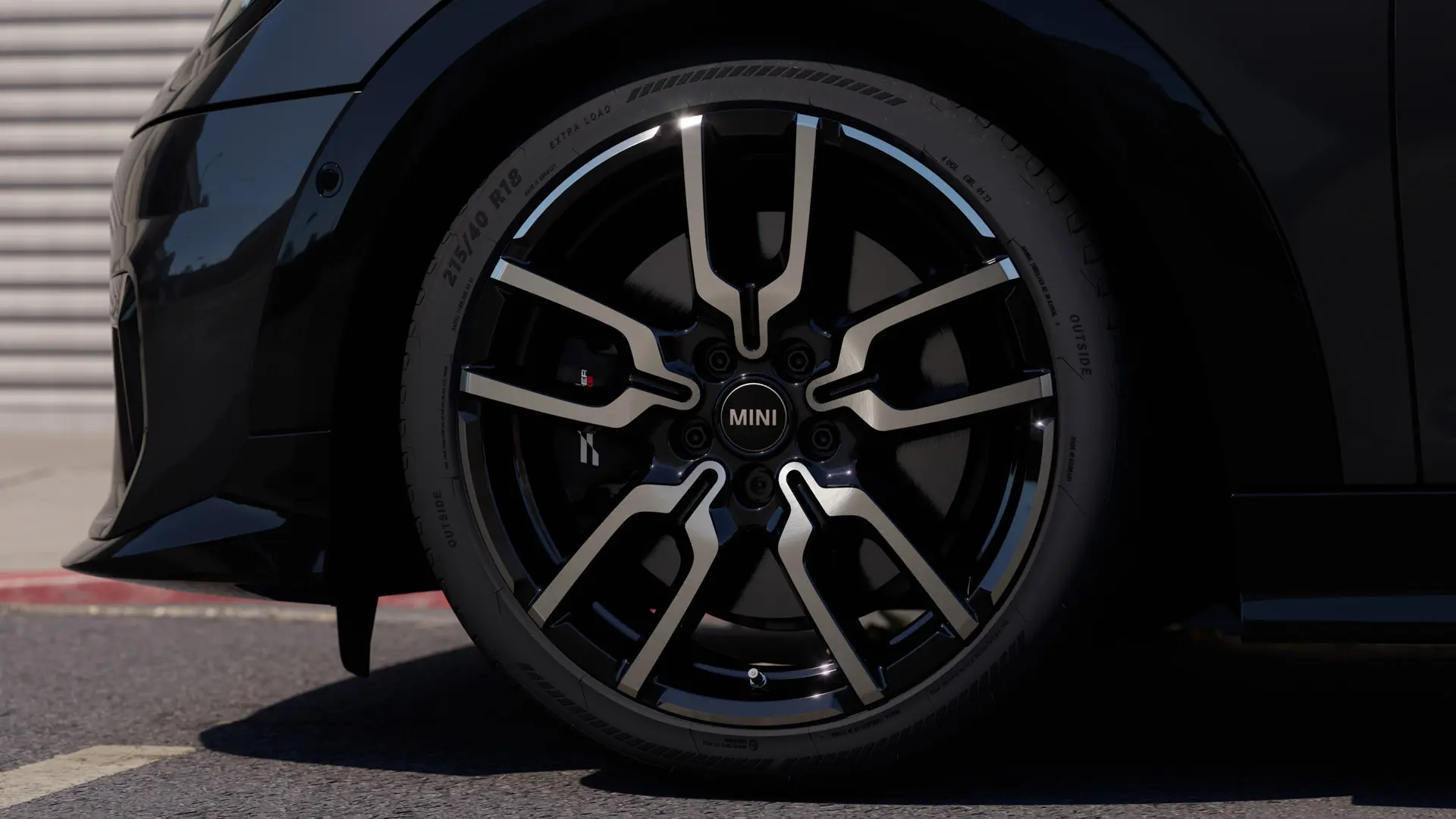 Nærbillede af JCW alufælg I Jet Black med Lap-eger, der viser fælgens karakteristiske design med åbne eger. 