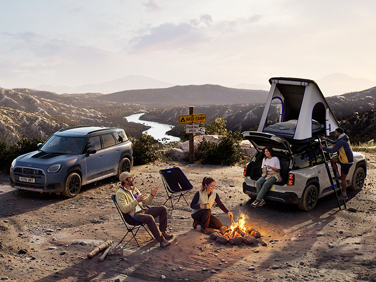 Billede af to MINI Countryman Untamed Edition-køretøjer på et bjerg i solnedgangen.